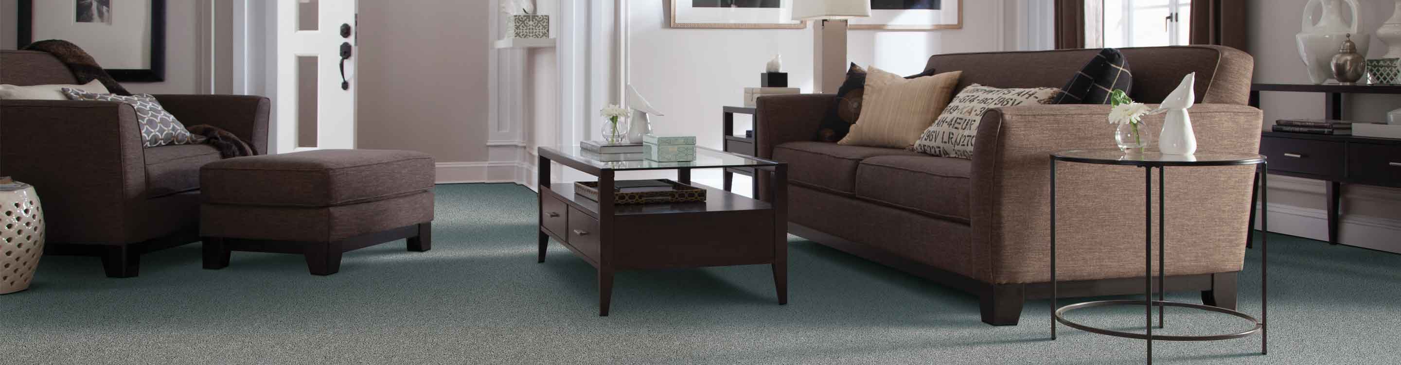 Gray carpet in a living room with brown furniture